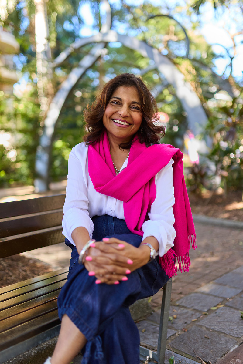 Carolyn Vincent smiling outdoors, wearing a bright pink scarf